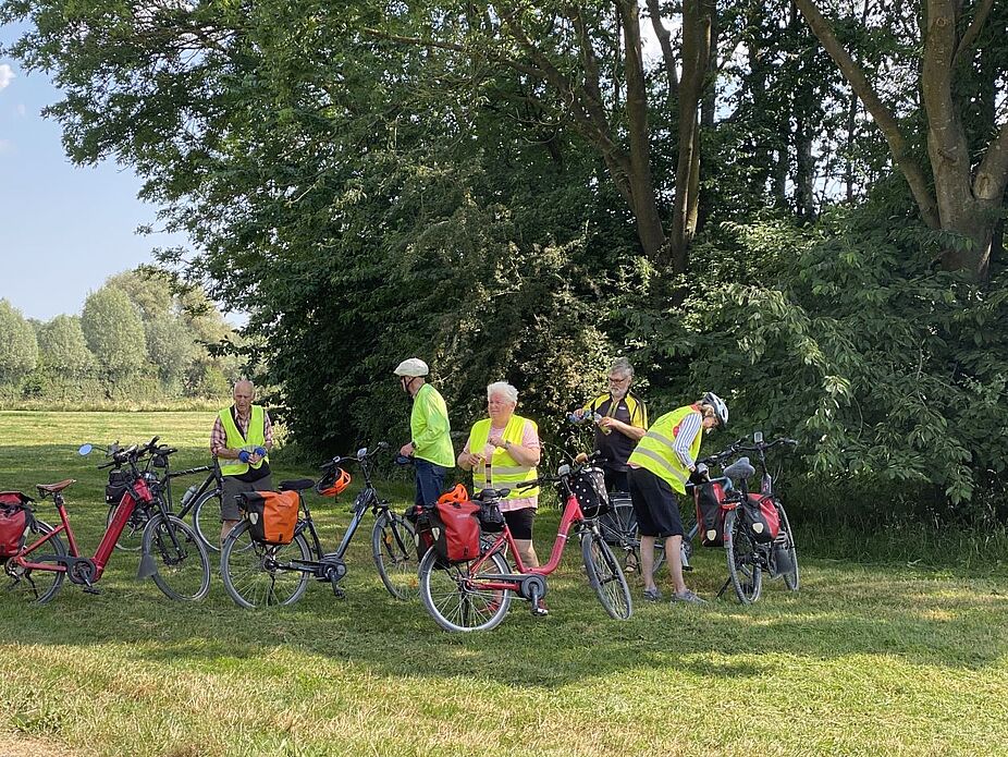 Erste Pause am Auesee unter schattenspendenden Sträuchern Ein Teil der Gruppe steht unter schattenspendenden Sträuchern