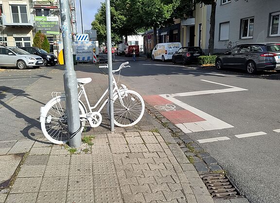 Ein weiß angemaltes Fahrrad an einem Laternenpfahl